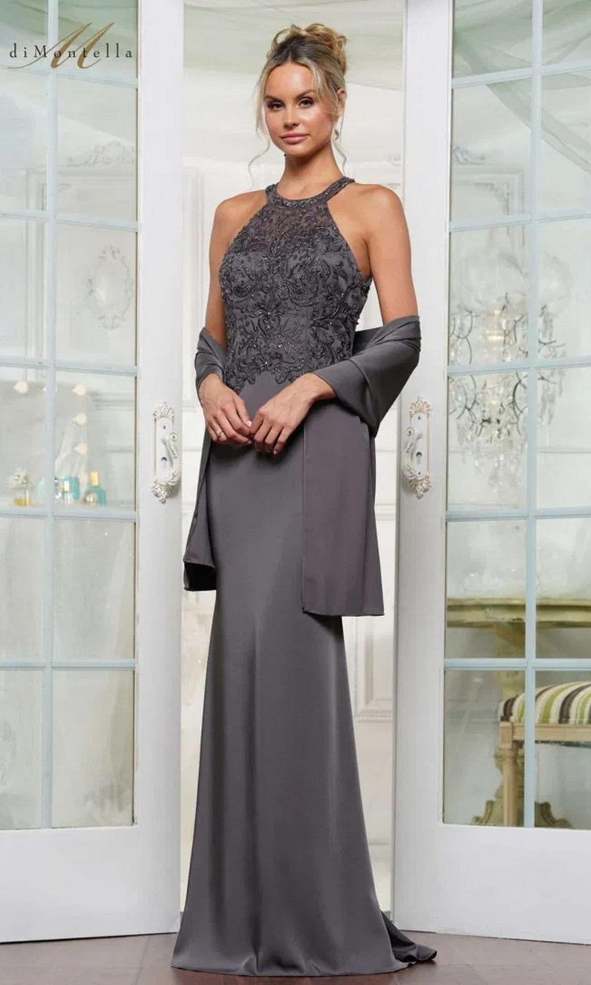 A woman in the charcoal Long Formal Dress: Rina Di Montella RD2755 featuring an embroidered bodice and matching shawl stands before double glass doors.